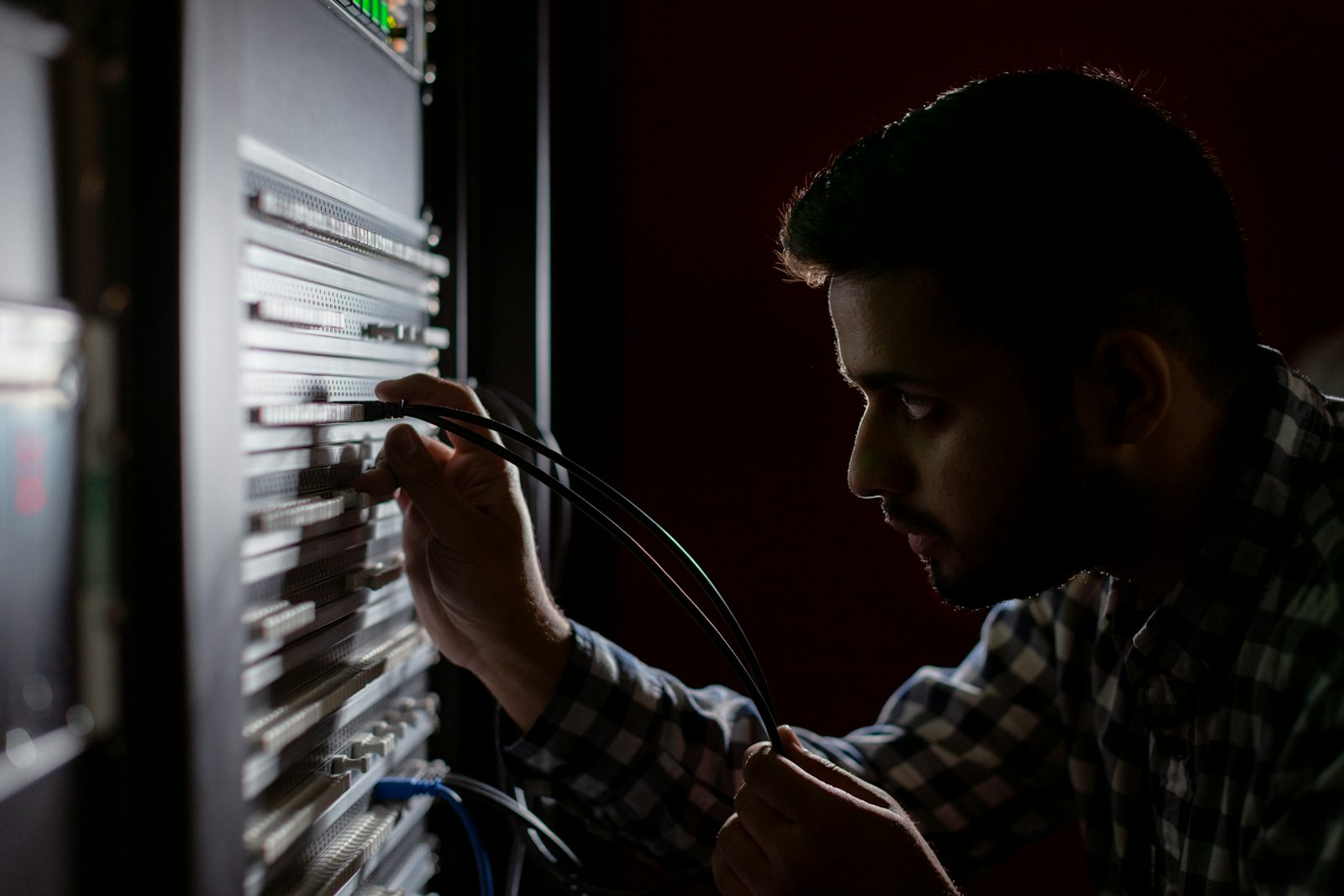 An IT technician working at a rack of networking equipment