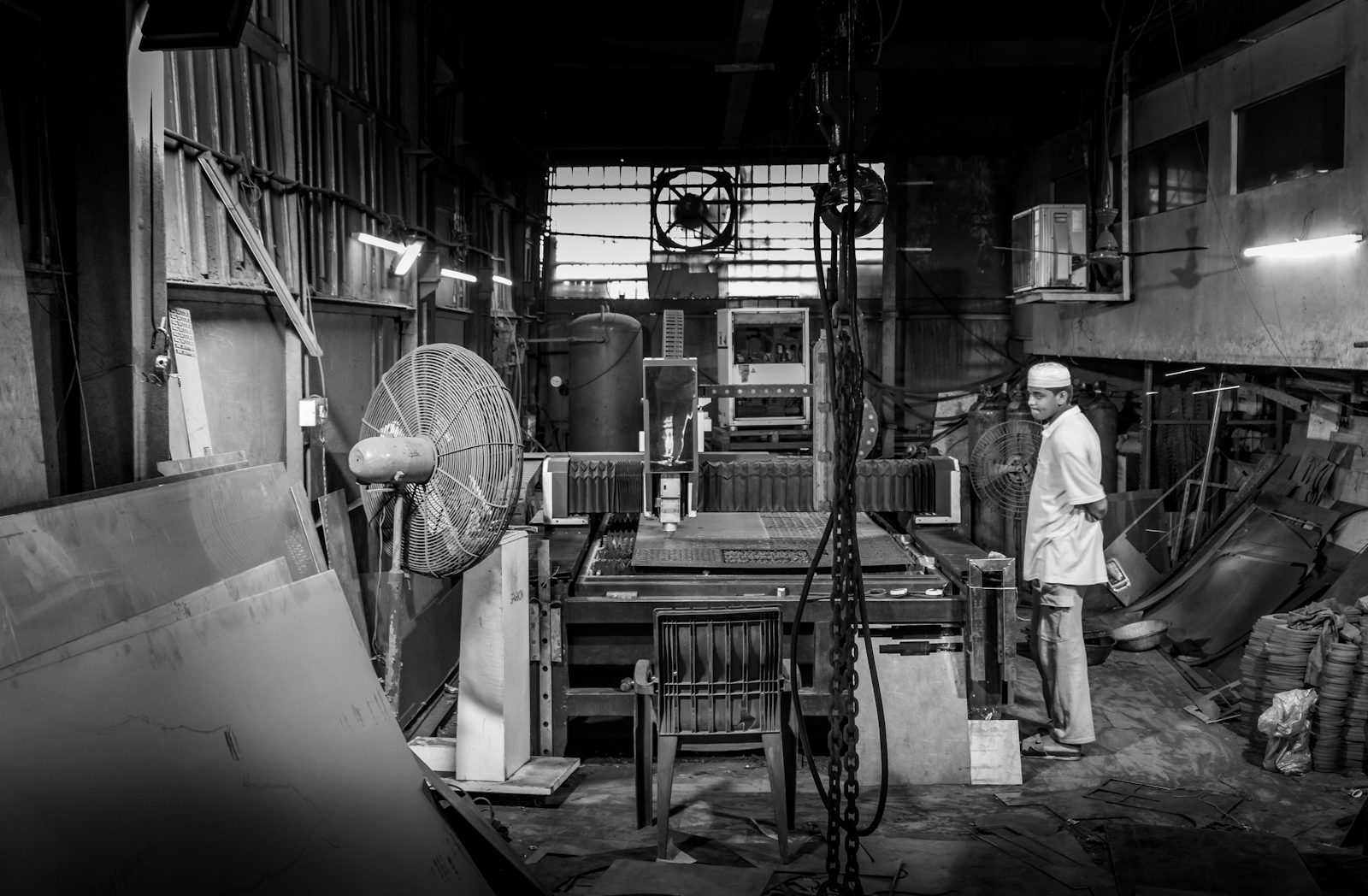 A machinist in a small, cluttered industrial workshop